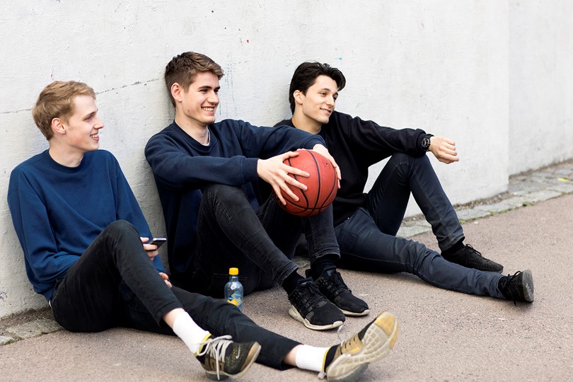 Tre mannlige studenter med basketball. Foto.